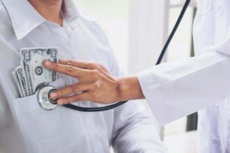 Doctor received corruption money, hand putting money in patient pocket form of dollar banknotes, Bribery and corruption in Health Care Industry.